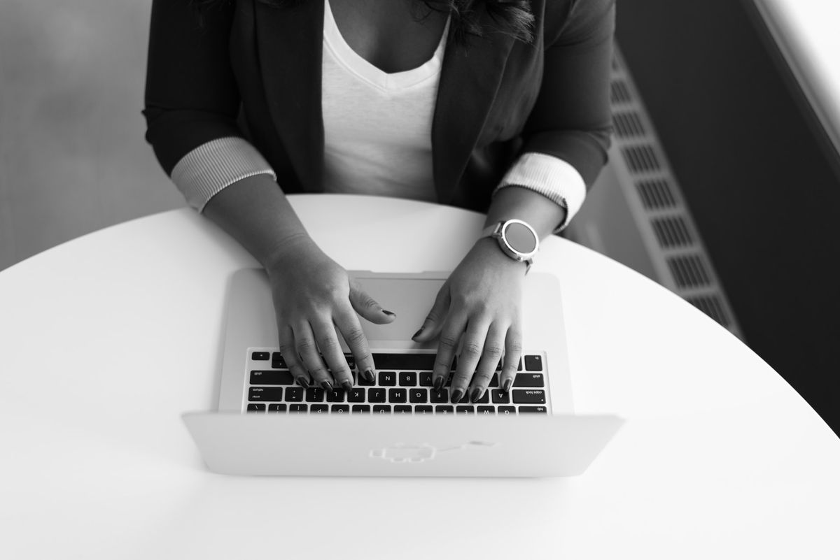 mustavalkoinen kuva naisesta, joka käyttää kannettavaa tietokonetta