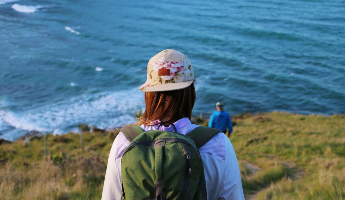 Offcuti mütsi kandev naine kõnnib ookeani poole